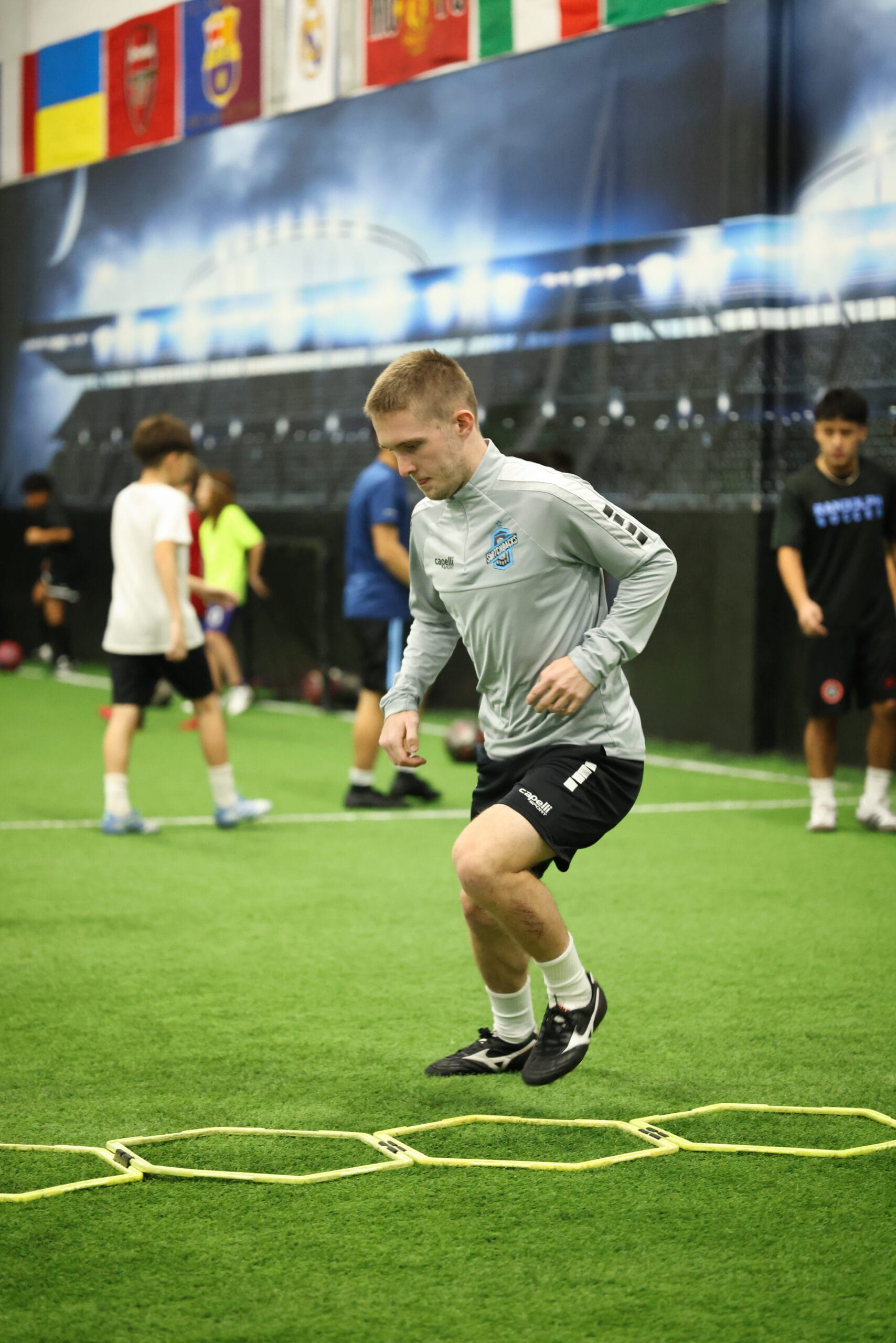 5K2A0338 Soccer coach focused on movement mechanics during agility ladder drill at Pro Soccer Academy