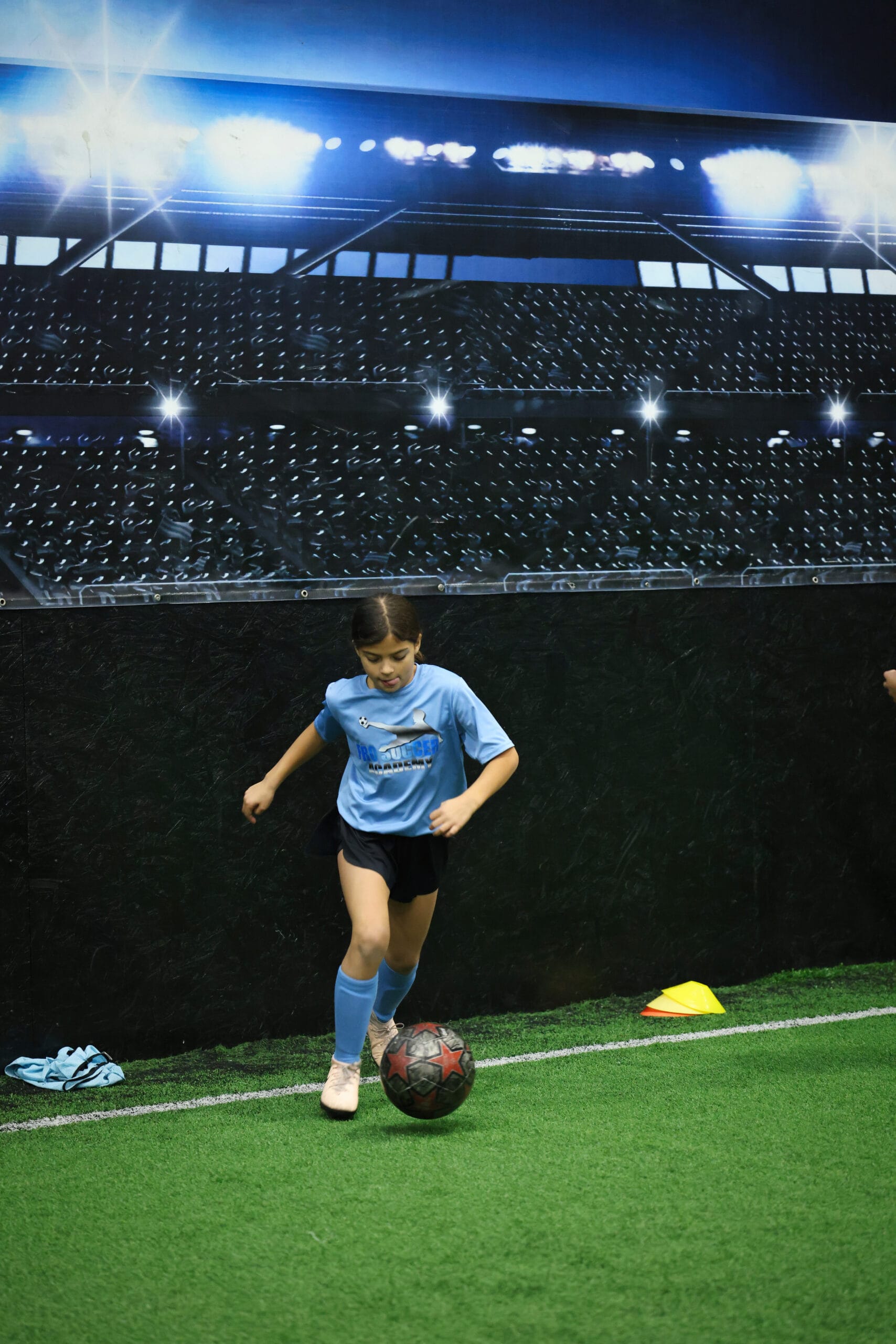 5K2A8758 Youth soccer player dribbling the ball along the wall during indoor soccer training in New Jersey