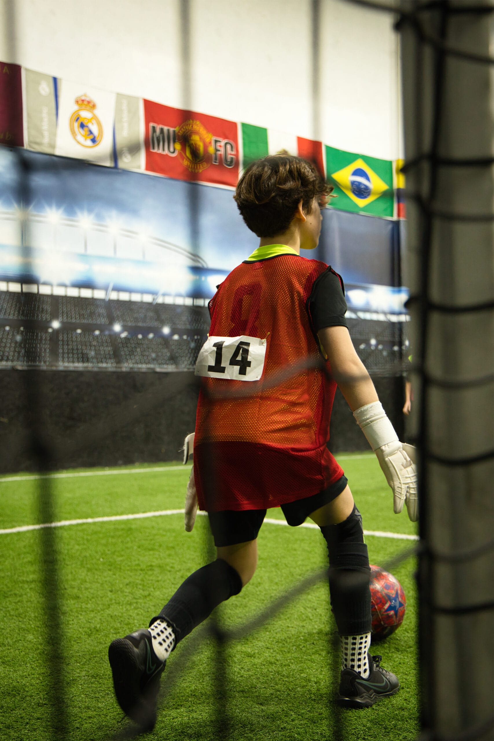 4Q8A0167 Youth goalkeeper wearing number 14 preparing to play ball inside Pro Soccer Academy indoor facility
