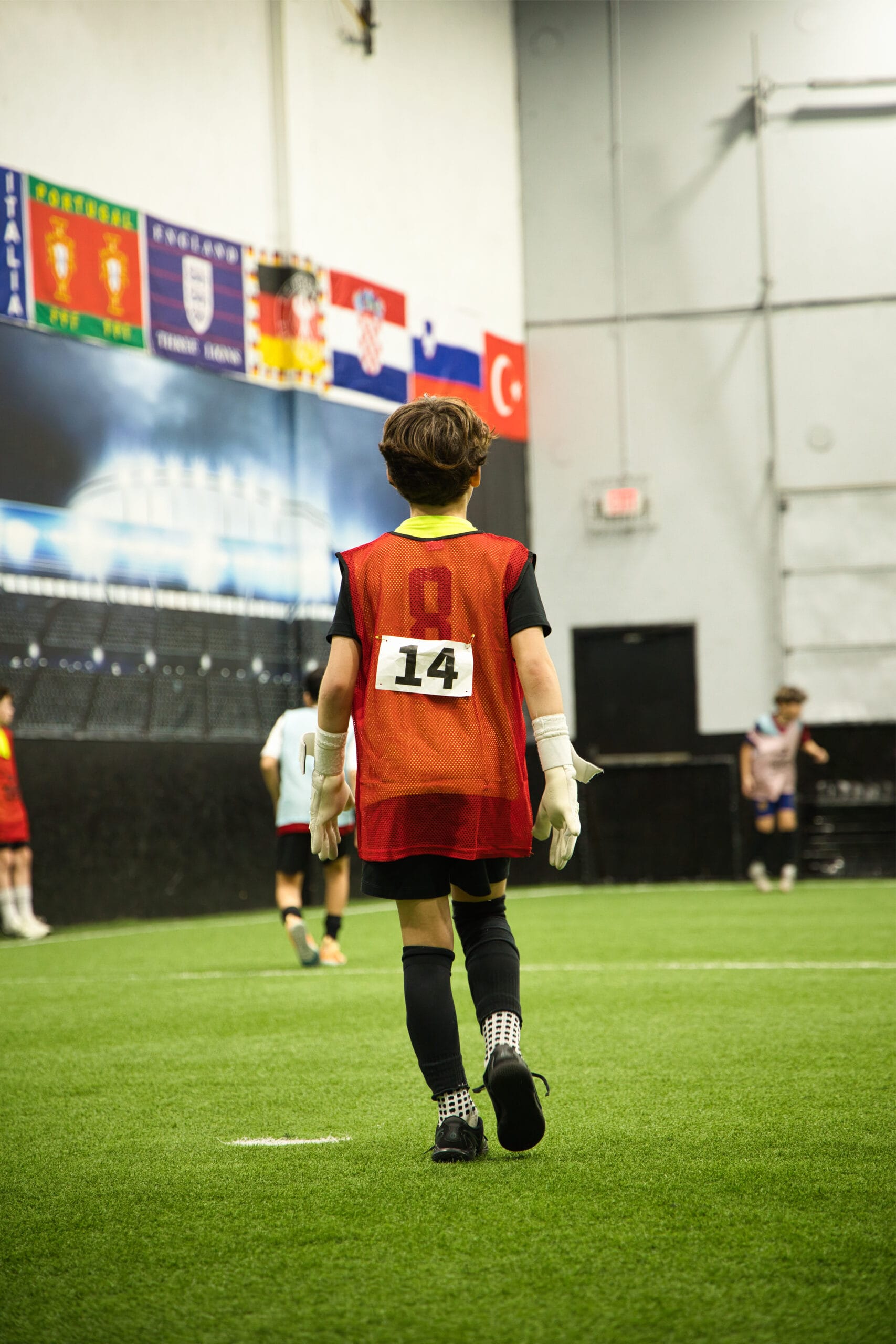 4Q8A0170 Youth goalkeeper wearing number 14 walking onto indoor field during Pro Soccer Academy session