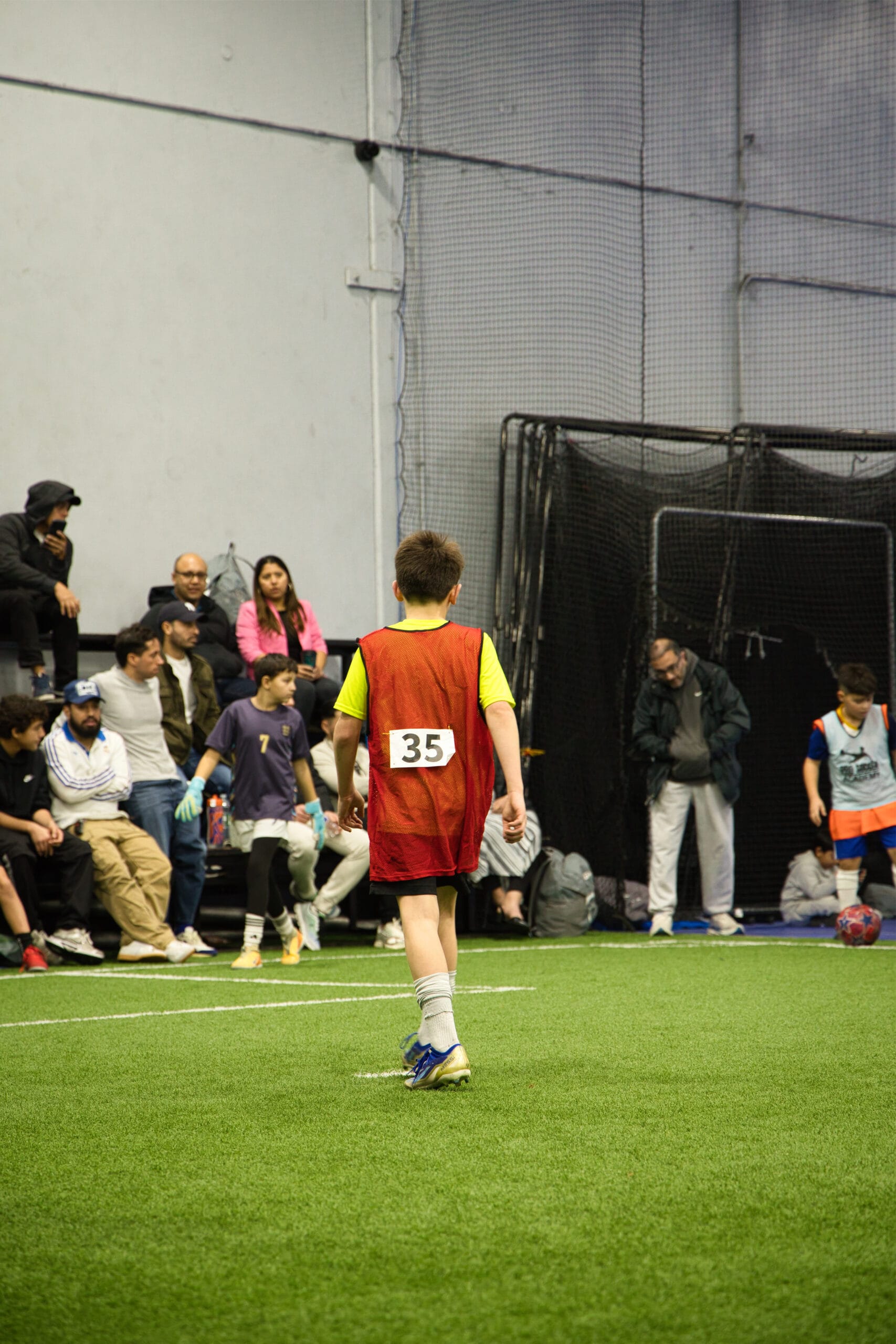 4Q8A0195 Young player wearing number 35 in red bib walking on indoor turf at Pro Soccer Academy