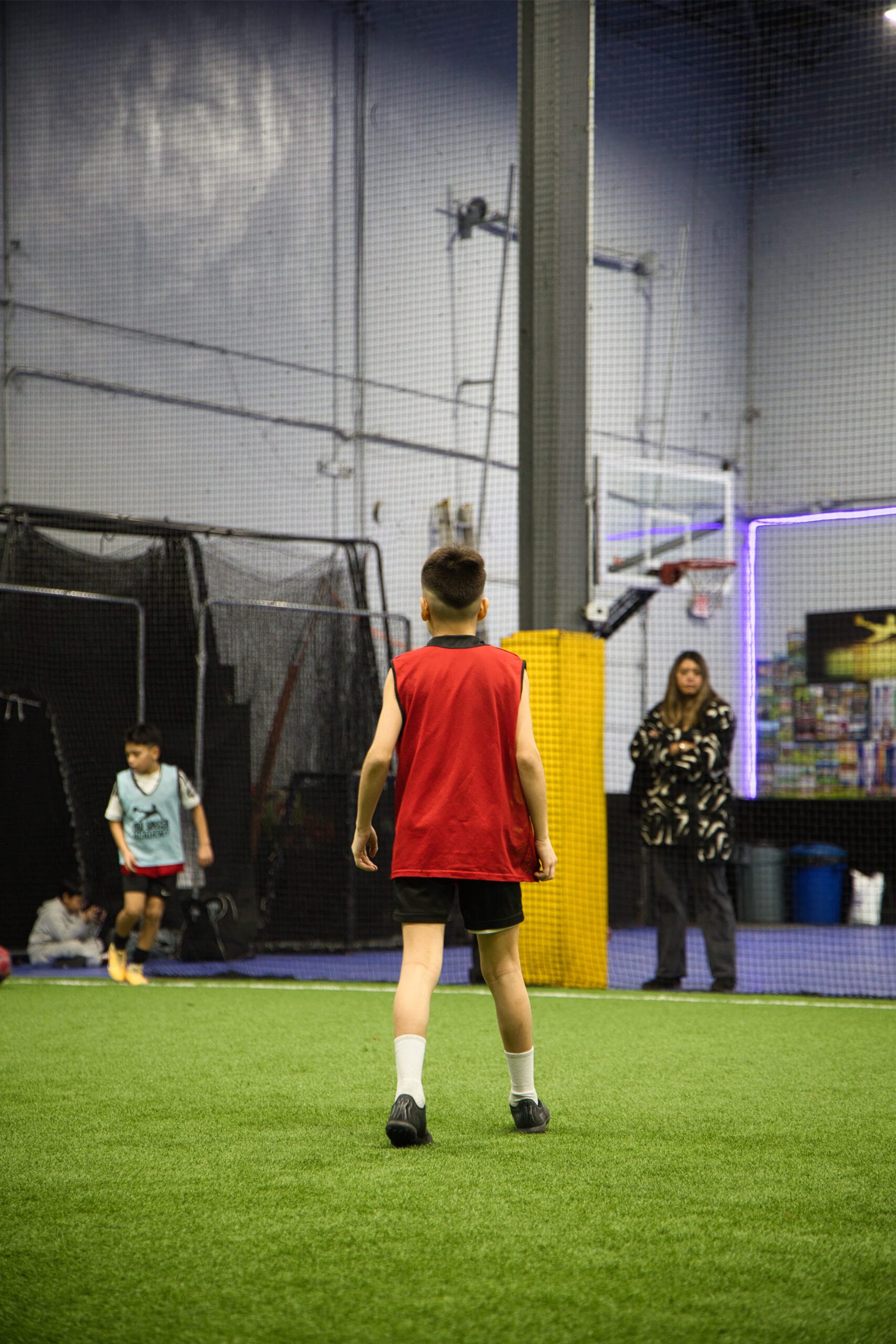4Q8A0211 Young player in red Pro Soccer Academy bib dribbling past defender on indoor turf