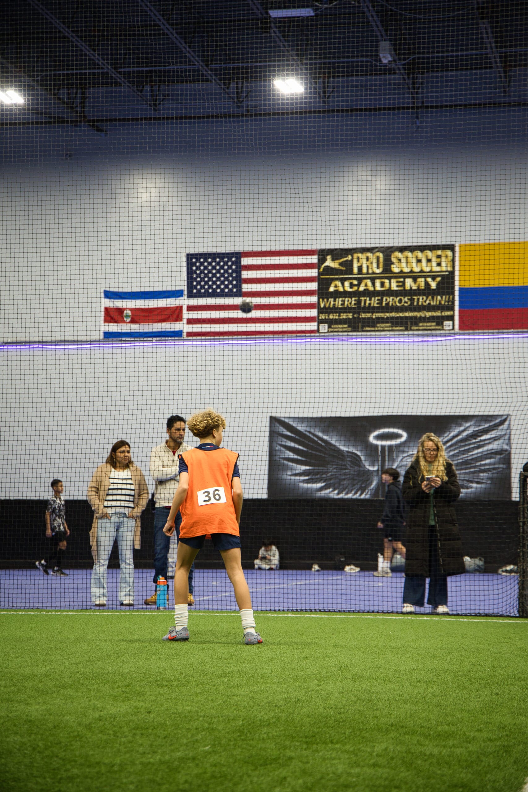 4Q8A0258 Youth soccer player wearing number 36 orange pinnie preparing for play on indoor turf at Pro Soccer Academy.