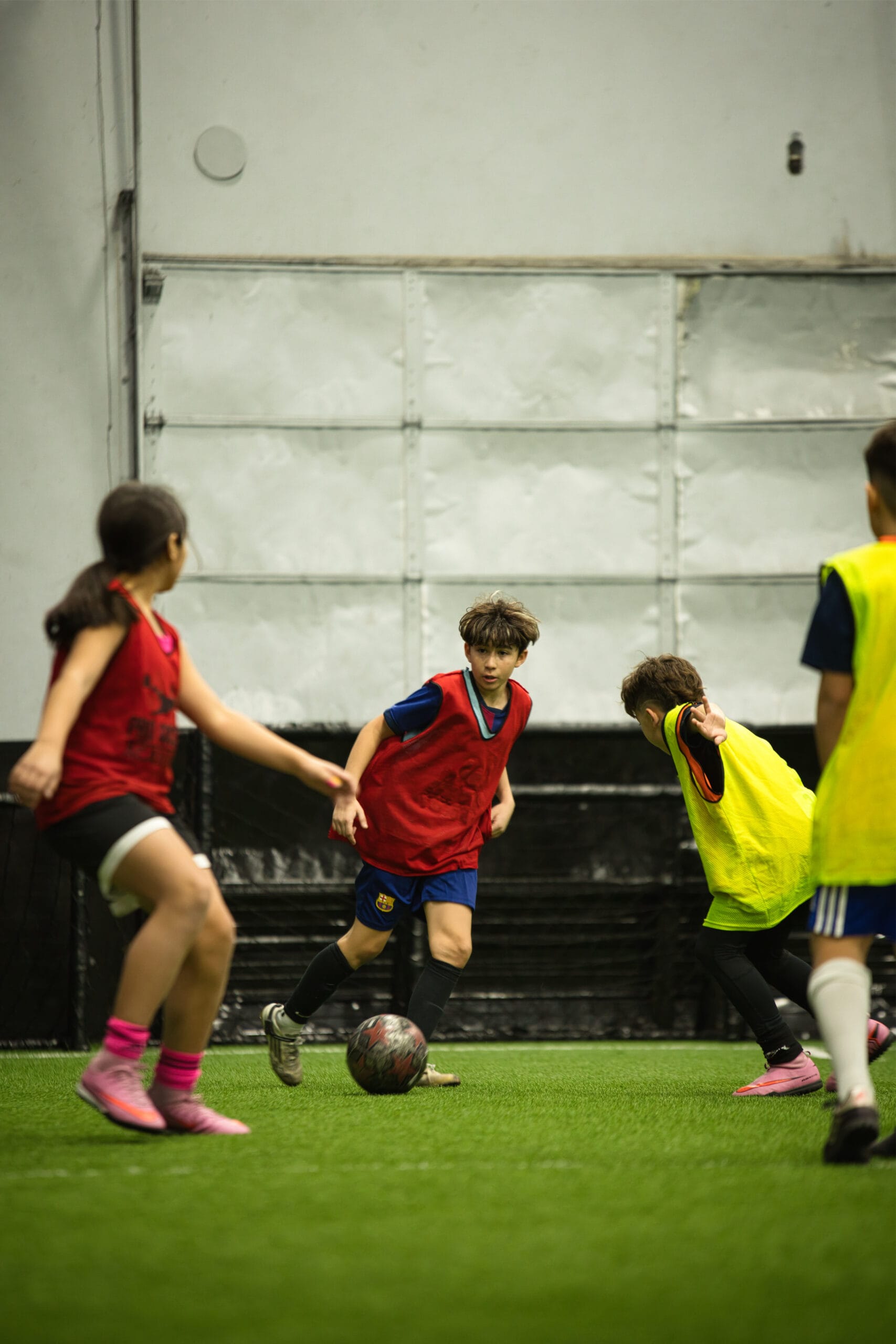 4Q8A0305 Youth soccer player dribbling ball between defenders during indoor Pro Soccer Academy competitive tryout match.