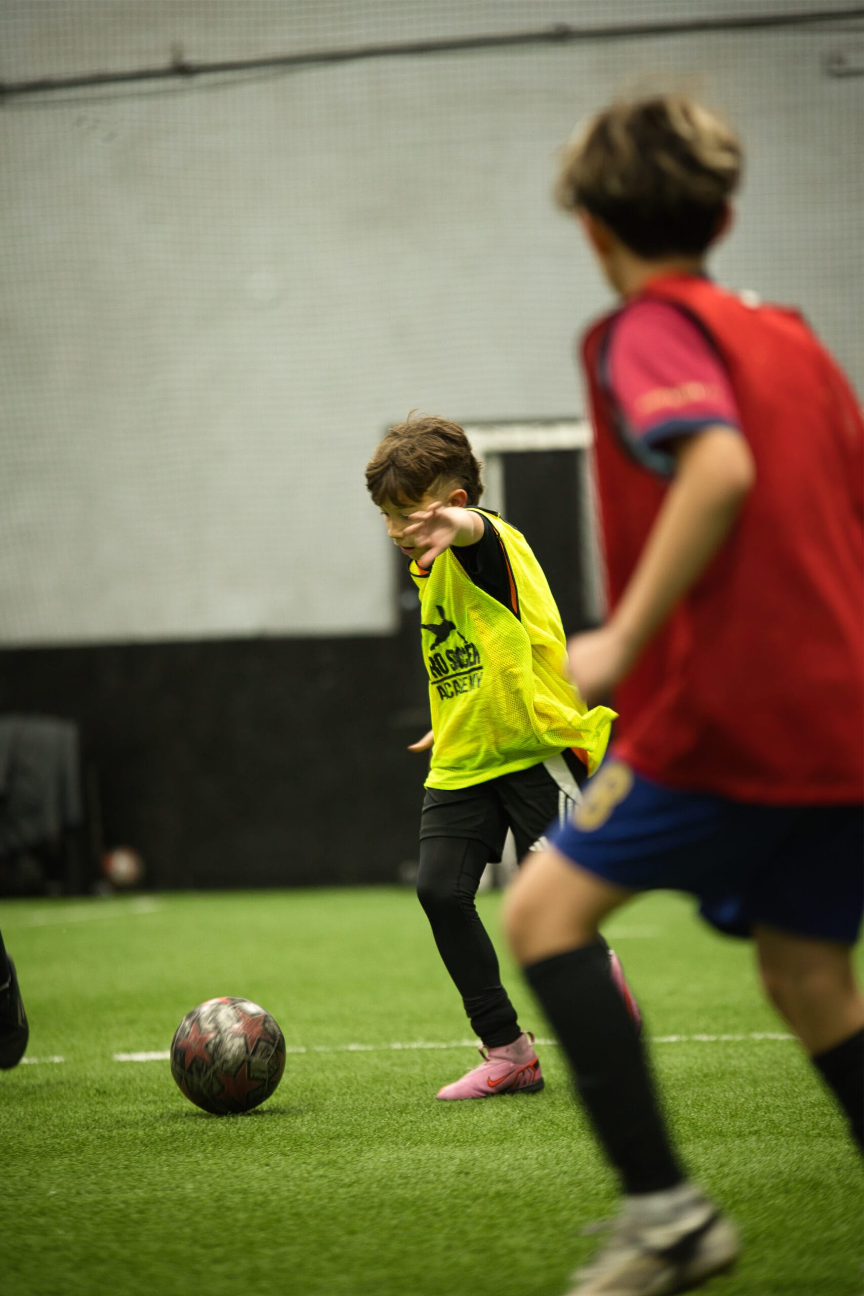 4Q8A0323 Youth player in yellow Pro Soccer Academy pinnie controlling the ball under pressure during indoor game.