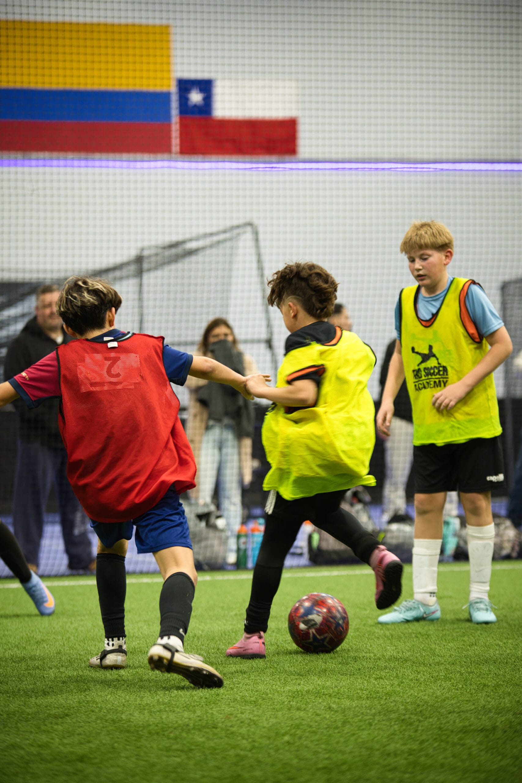 4Q8A0333 Youth players competing for possession under indoor arena lights at Pro Soccer Academy.