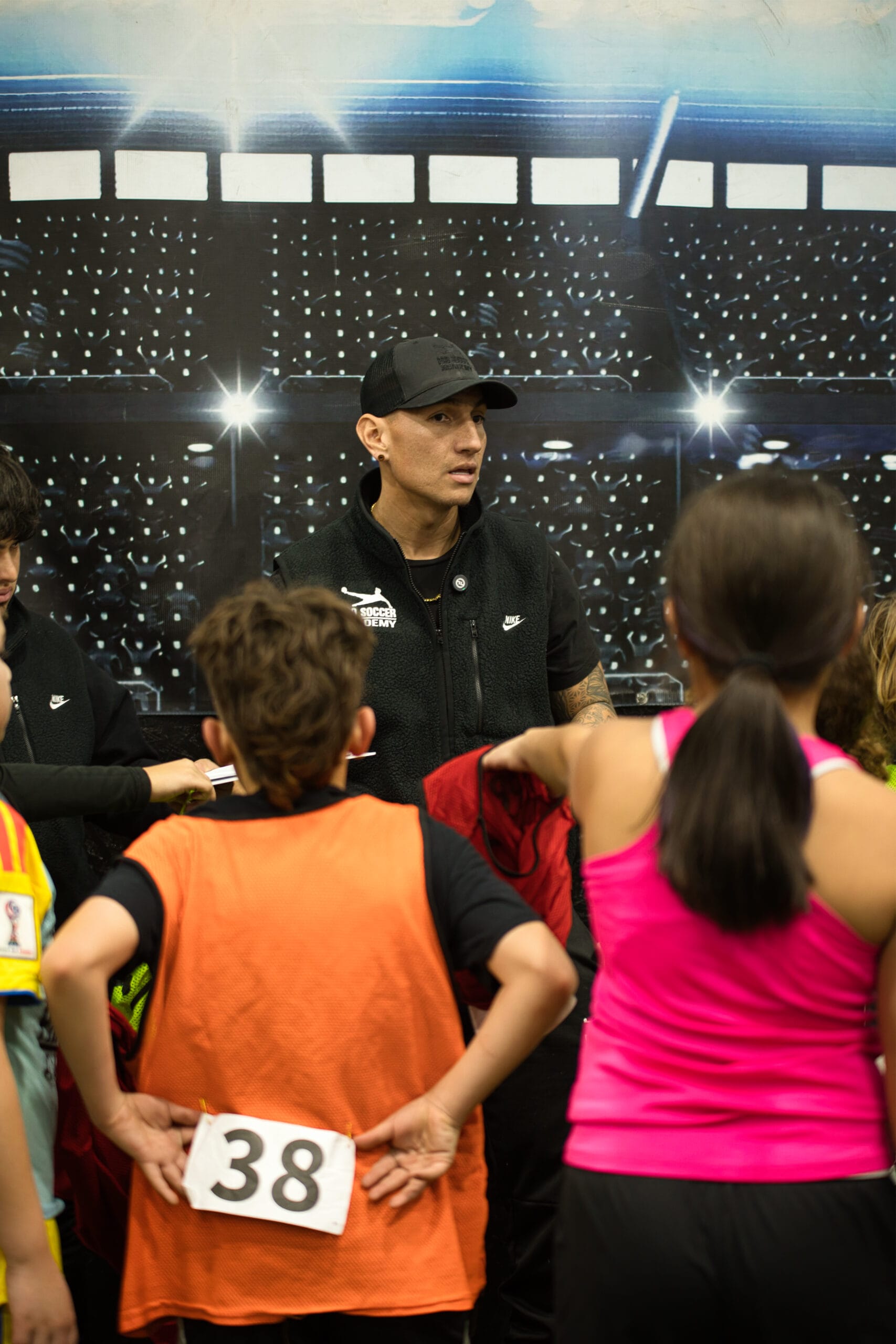 4Q8A0335 Pro Soccer Academy coach giving tactical instructions to youth players during indoor team huddle.