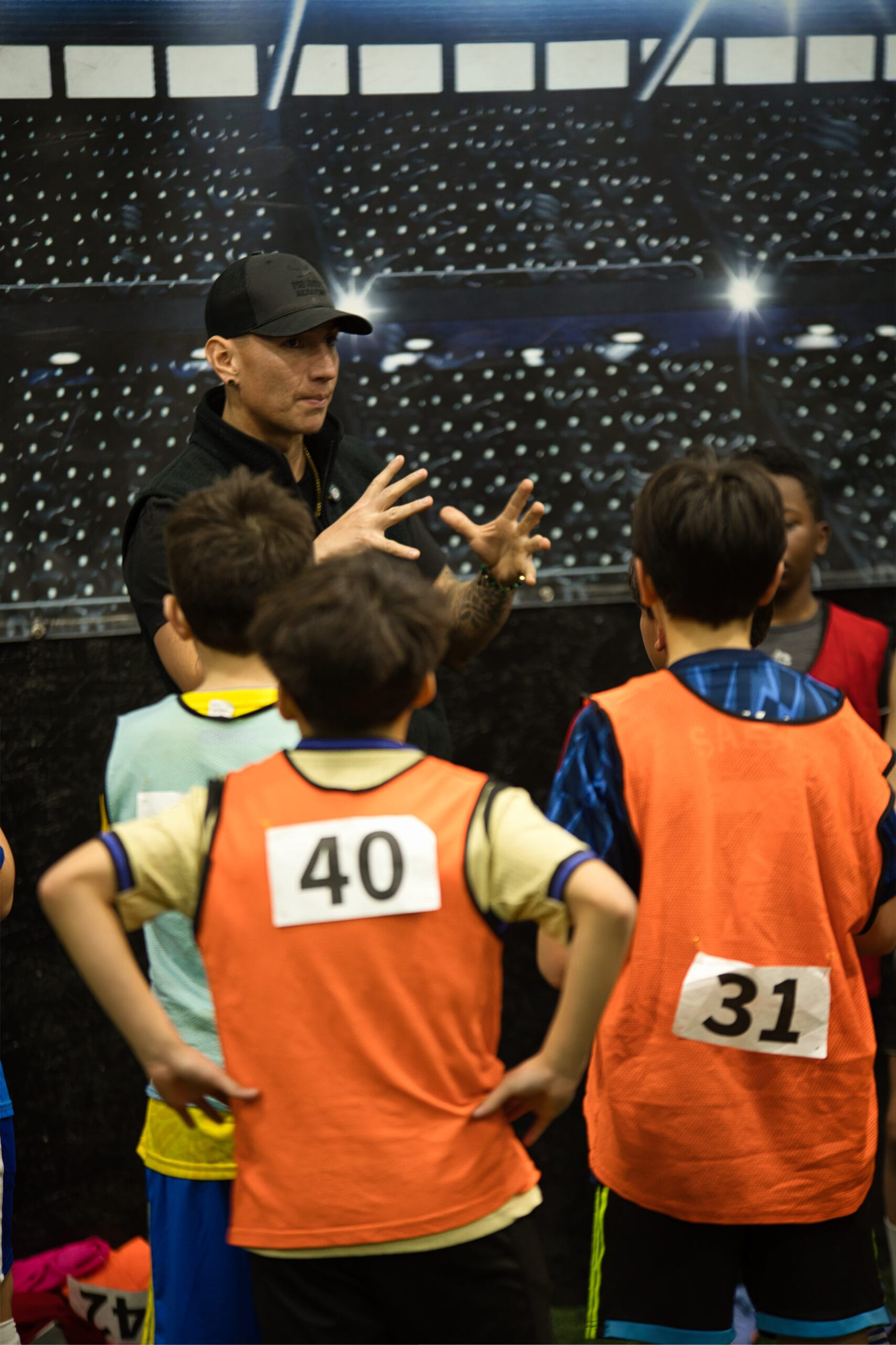 4Q8A0368 Pro Soccer Academy coach demonstrating hand gestures while addressing youth players in team huddle.
