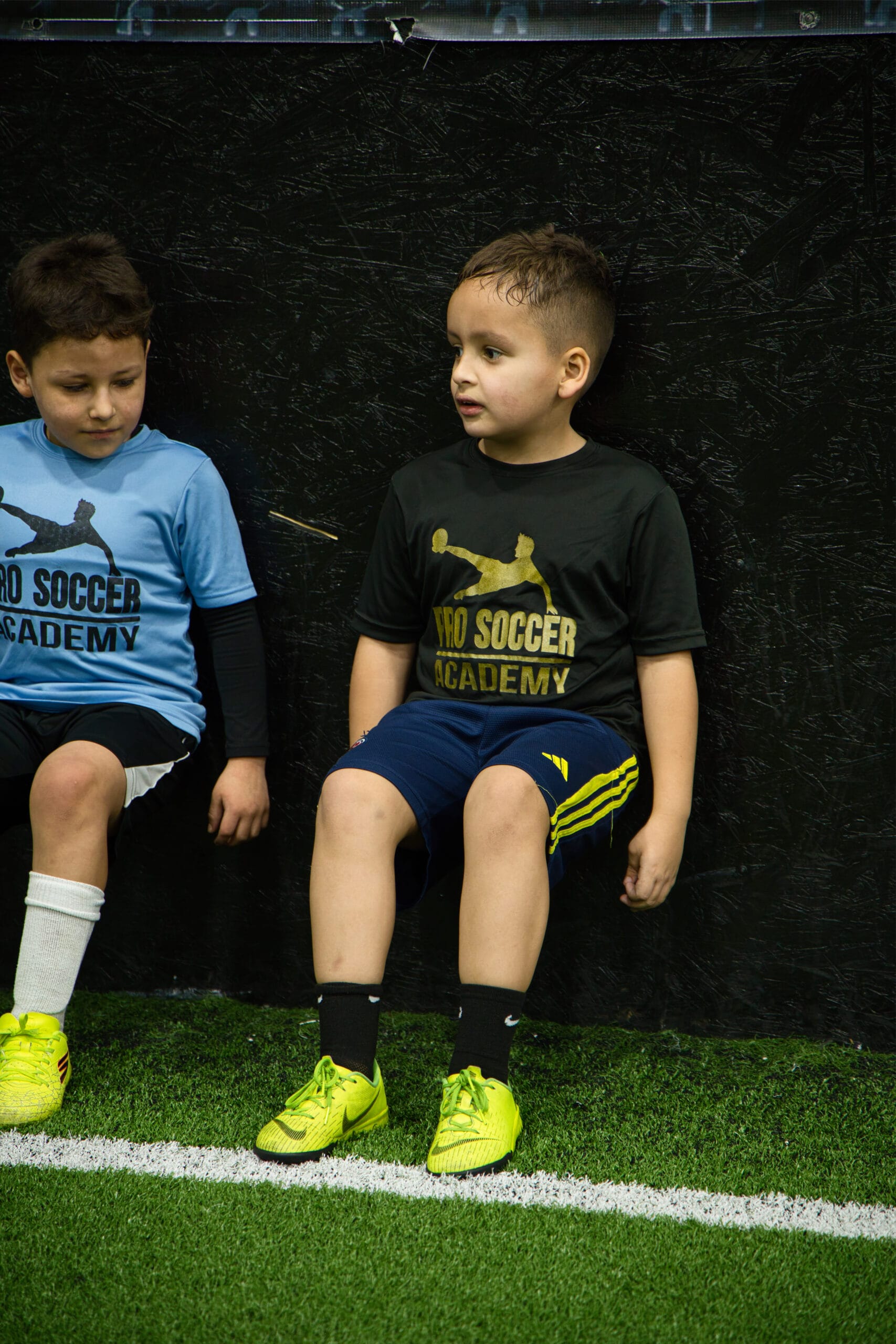 4Q8A0296 Youth soccer players performing wall sits for leg strength and conditioning at Pro Soccer Academy indoor training facility.