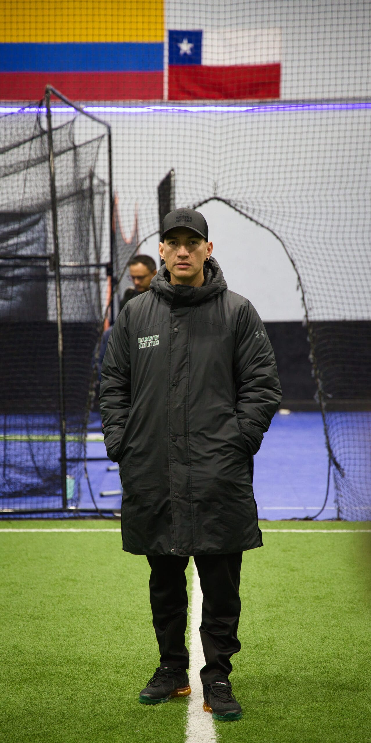 Soccer coach standing on indoor field at Pro Soccer Academy overseeing youth training session
