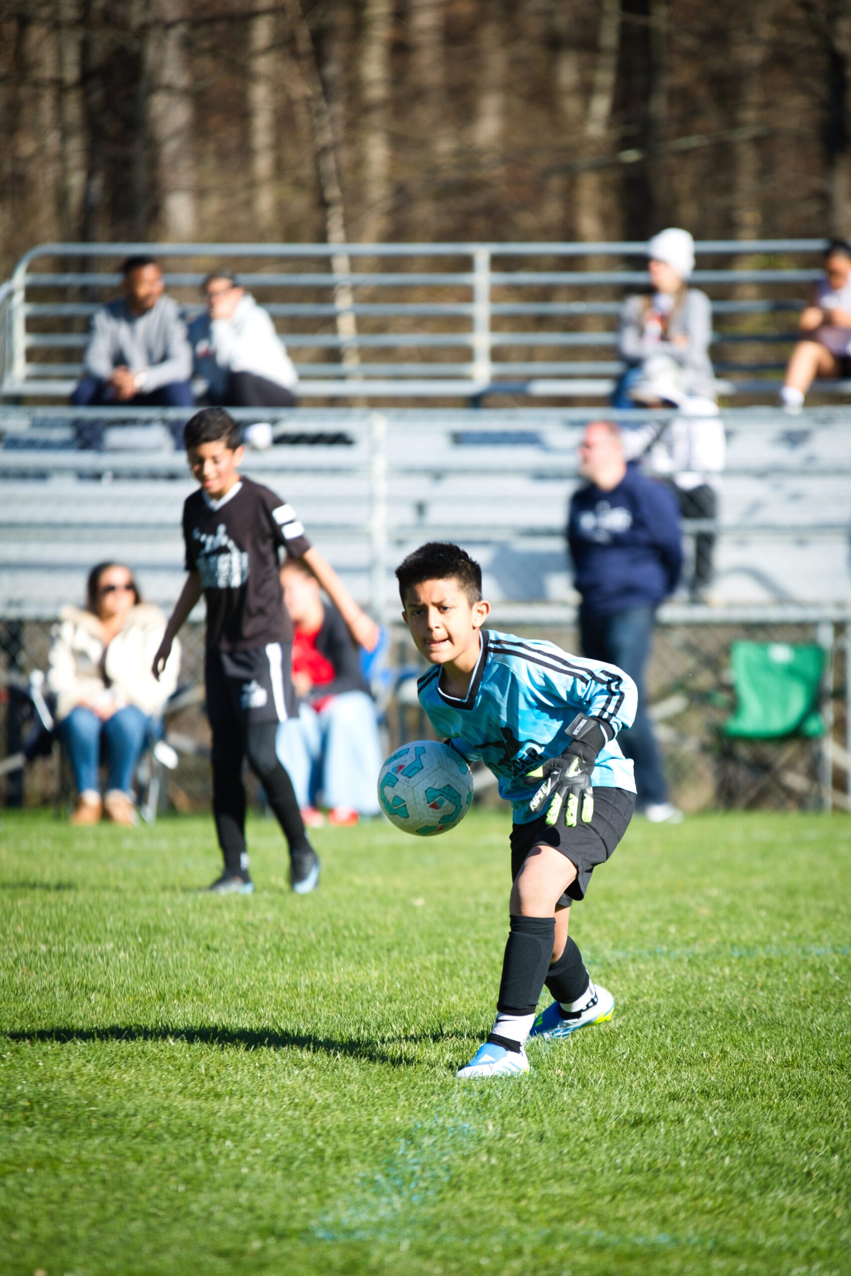 Youth goalkeeper controlling soccer ball near goal during indoor training at Pro Soccer Academy