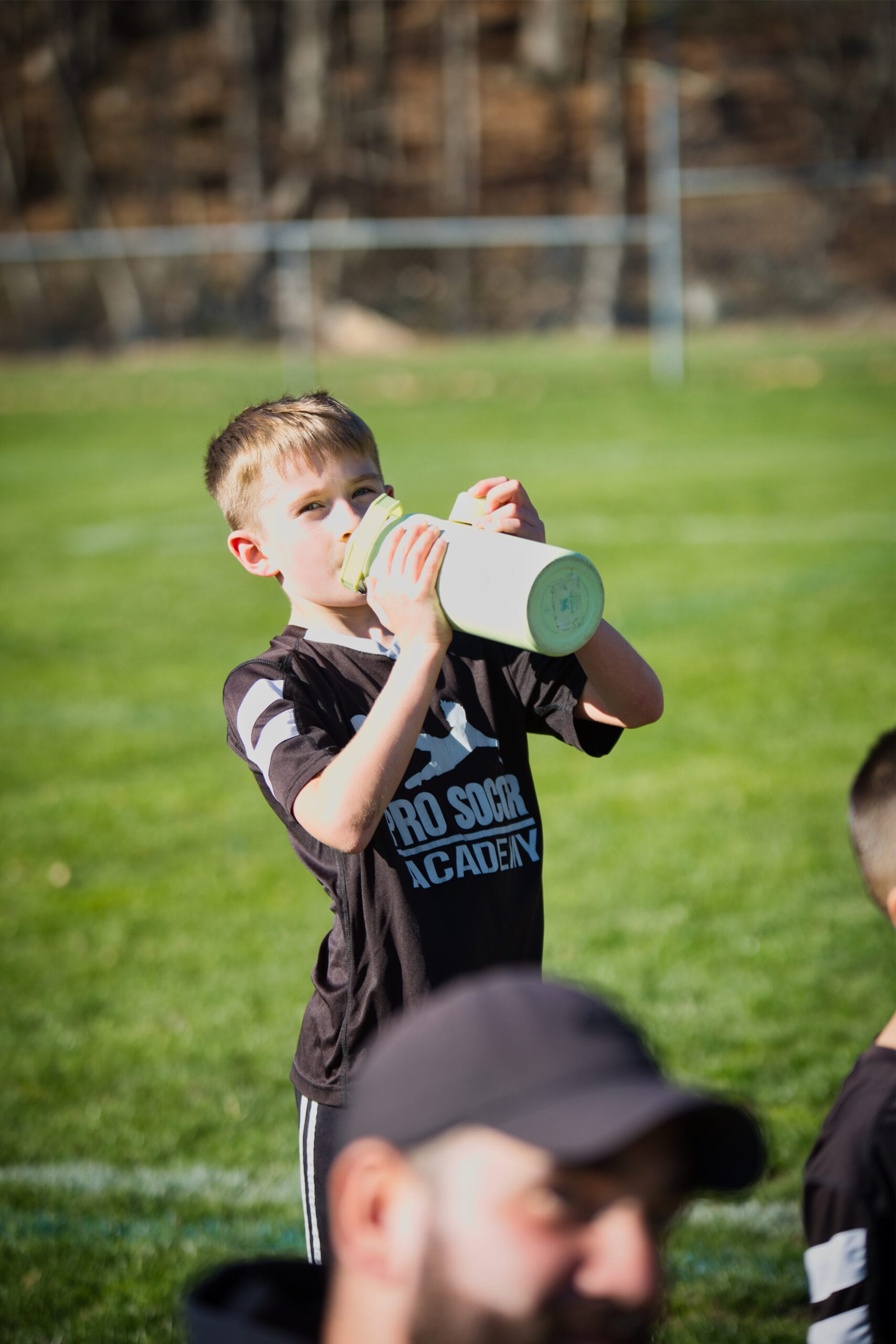 Youth soccer player running during indoor training session at Pro Soccer Academy with spectators in background