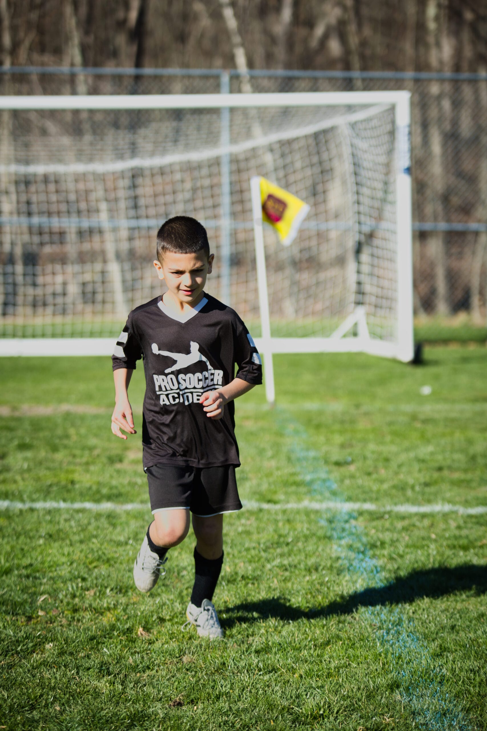 Youth soccer player running during indoor training session at Pro Soccer Academy with spectators in background